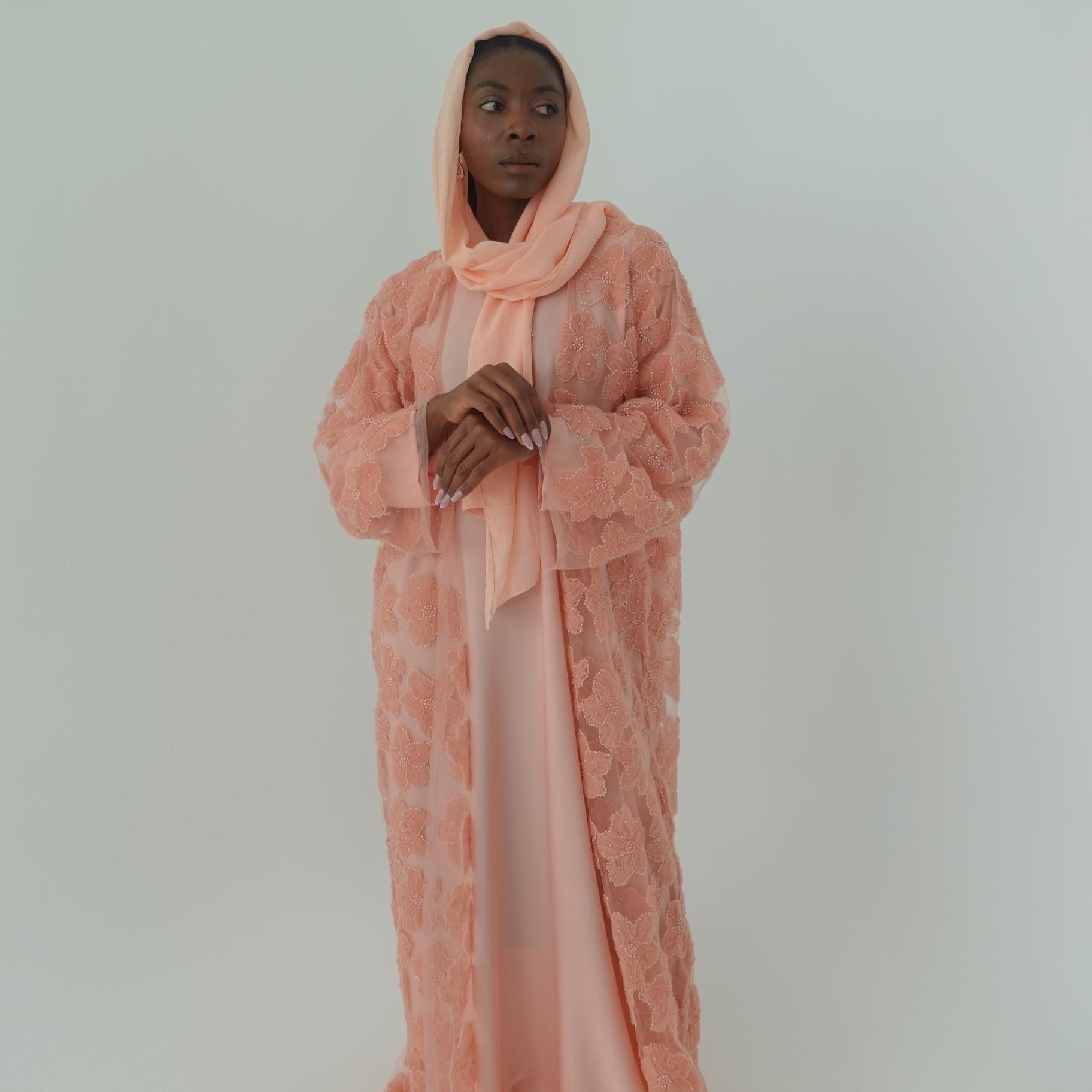 Person wearing a pink lace outfit on a light gray background