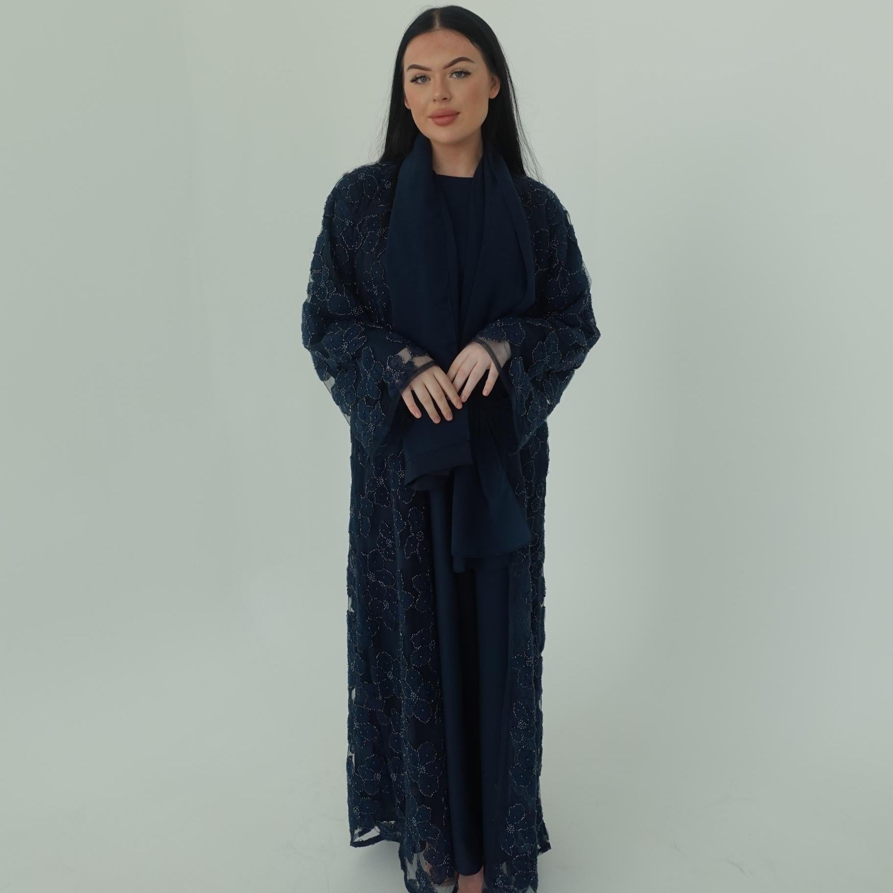 Woman wearing a dark blue lace dress against a white background