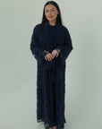 Woman wearing a dark blue lace dress against a white background