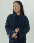 Woman wearing a dark blue lace dress against a plain background