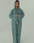 Person wearing a green hooded outfit on a plain background