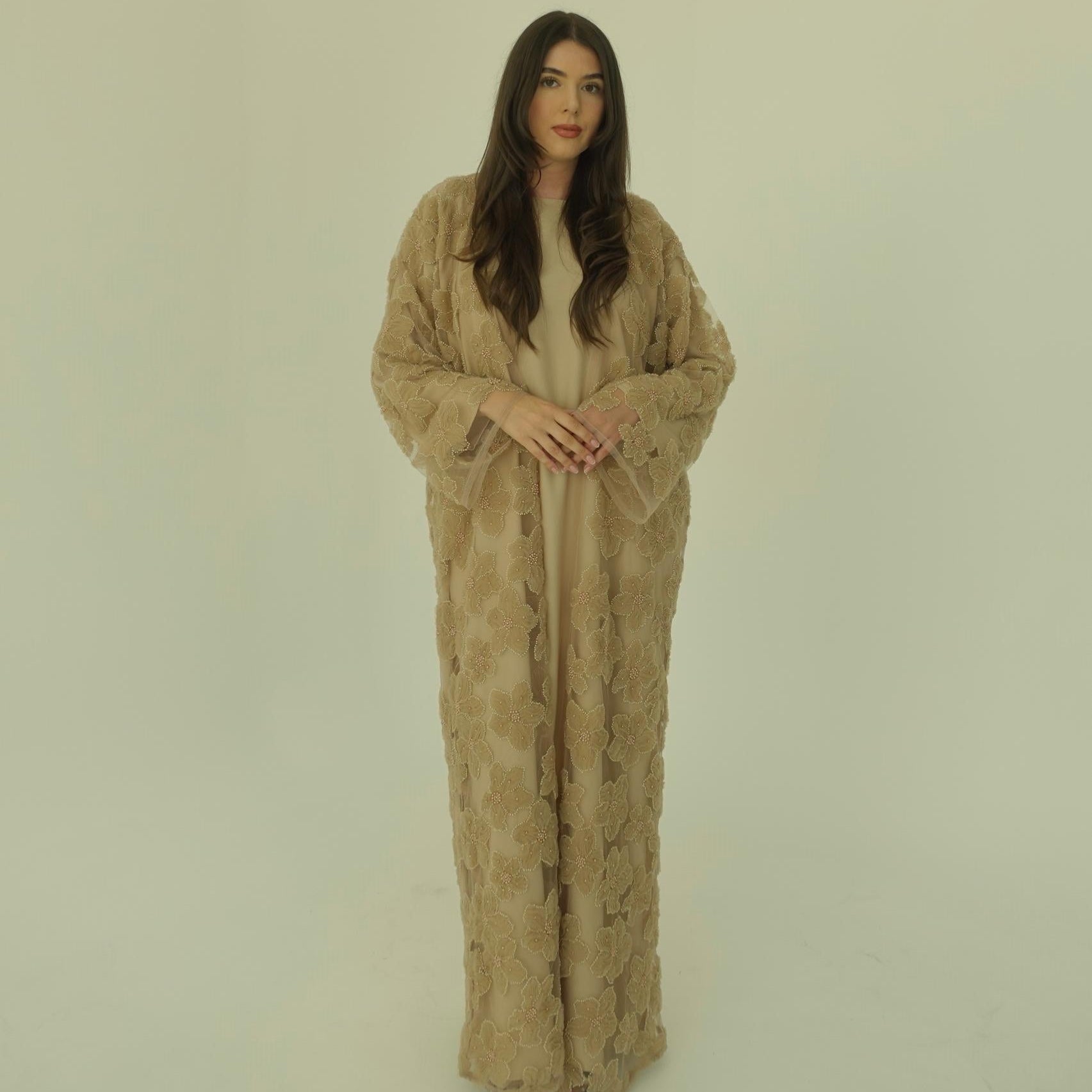 Woman wearing a beige patterned dress against a plain background