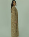 Woman wearing a long beige dress against a plain background