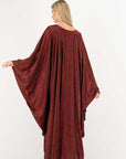 Woman wearing a burgundy long dress with a flowing design on a white background