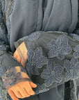 Gray embroidered garment with floral patterns on a yellow background