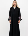 Black Liana Abaya with hand-sewn silver beads in a leaf and embroidery design pattern on the arms. Light pink, blue, and purple threads add color to the embroidery. Comes with a matching black hijab and popper buttons for closure.