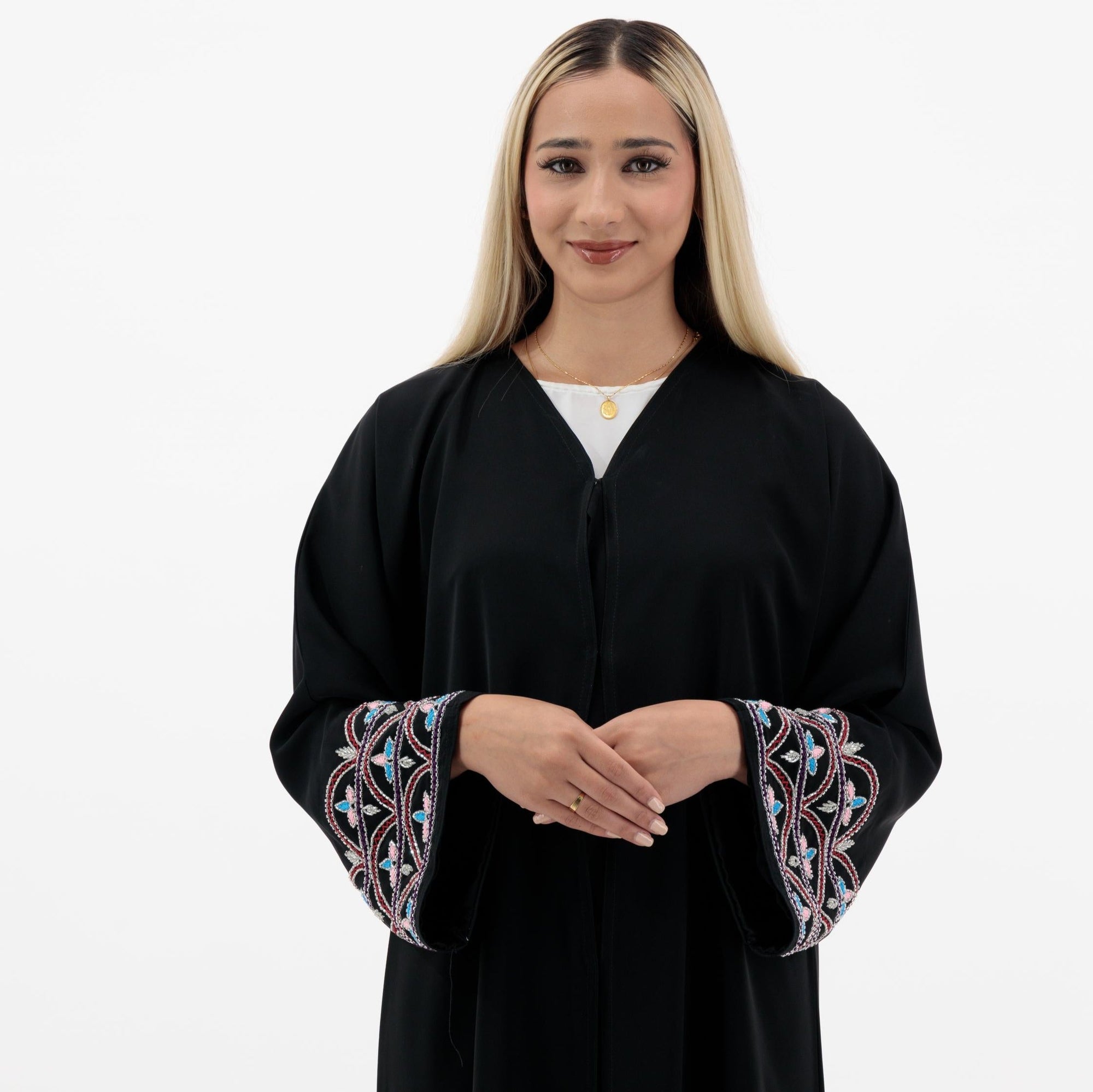 Black Liana Abaya with hand-sewn silver beads in a leaf and embroidery design pattern on the arms. Light pink, blue, and purple threads add color to the embroidery. Comes with a matching black hijab and popper buttons for closure.