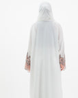 White abaya with silver beadwork and pink and brown embroidery on the sleeves. Made from crepe material with popper buttons, available in sizes 50-60, and includes a matching hijab.