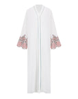 White abaya with silver beadwork and pink and brown embroidery on the sleeves. Made from crepe material with popper buttons, available in sizes 50-60, and includes a matching hijab.