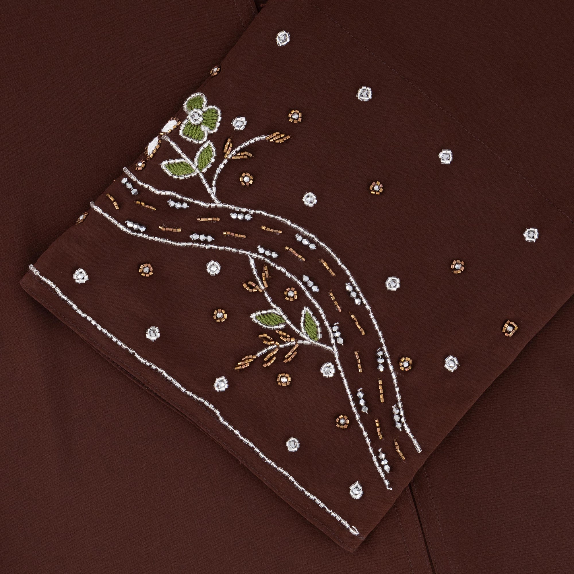 Reema Abaya available in Black, Vanilla, and Chocolate Brown with golden and silver beaded sleeves in a floral and leafy design. Made from crepe fabric with popper buttons, available in sizes 50-60. Includes a matching hijab.