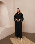 Reema Abaya available in Black, Vanilla, and Chocolate Brown with golden and silver beaded sleeves in a floral and leafy design. Made from crepe fabric with popper buttons, available in sizes 50-60. Includes a matching hijab.