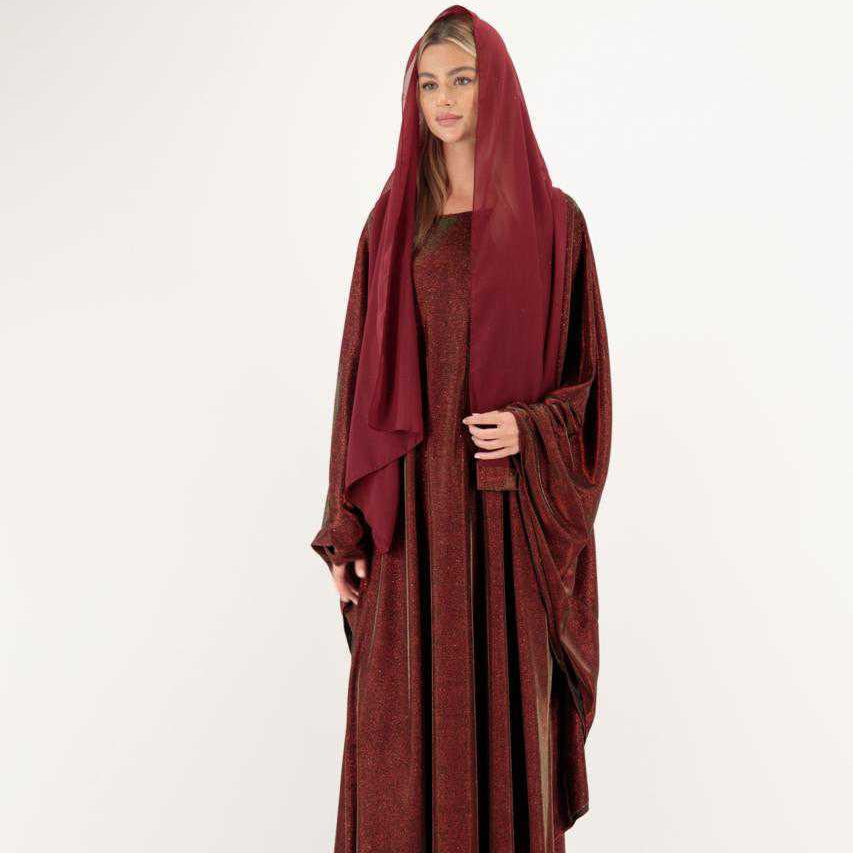 Woman wearing a long burgundy dress with a hood on a white background