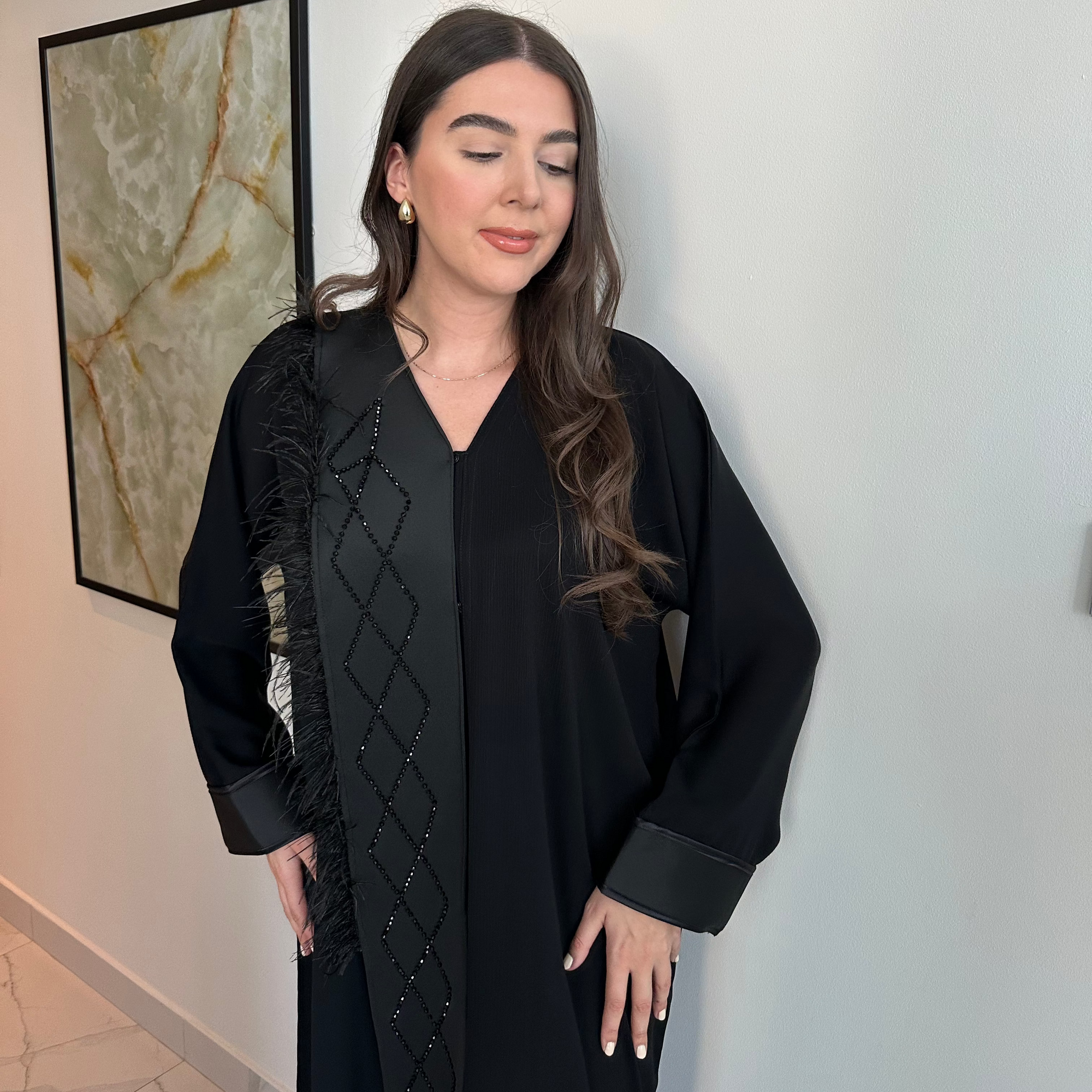 A luxurious black Nidha-lined open abaya featuring intricate black beaded and furry detailing, designed for elegance and comfort. Includes convenient popper buttons and a complimentary hijab for a polished look. Perfect for any occasion with a soft, breathable, and flowy fit.