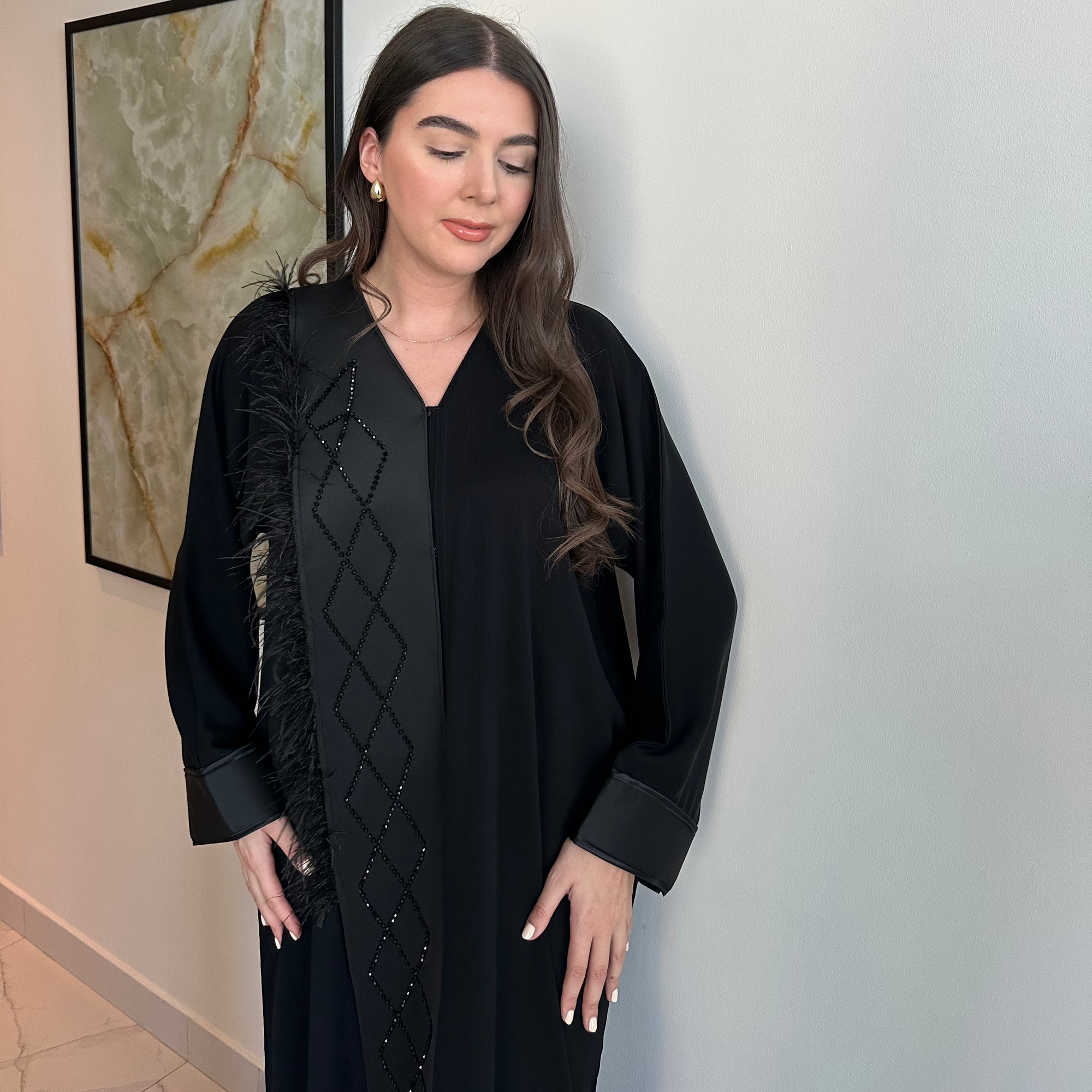 A luxurious black Nidha-lined open abaya featuring intricate black beaded and furry detailing, designed for elegance and comfort. Includes convenient popper buttons and a complimentary hijab for a polished look. Perfect for any occasion with a soft, breathable, and flowy fit.