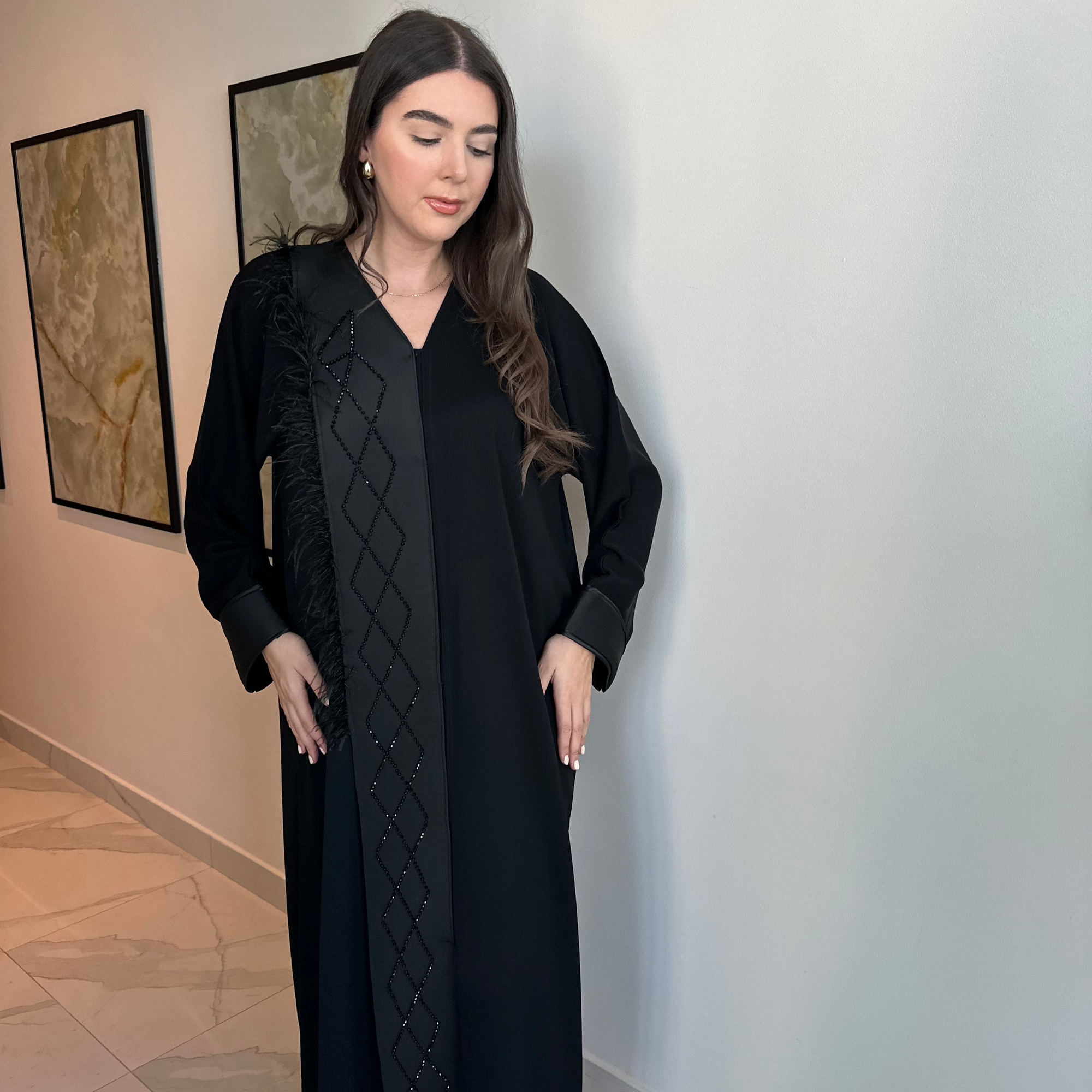 A luxurious black Nidha-lined open abaya featuring intricate black beaded and furry detailing, designed for elegance and comfort. Includes convenient popper buttons and a complimentary hijab for a polished look. Perfect for any occasion with a soft, breathable, and flowy fit.